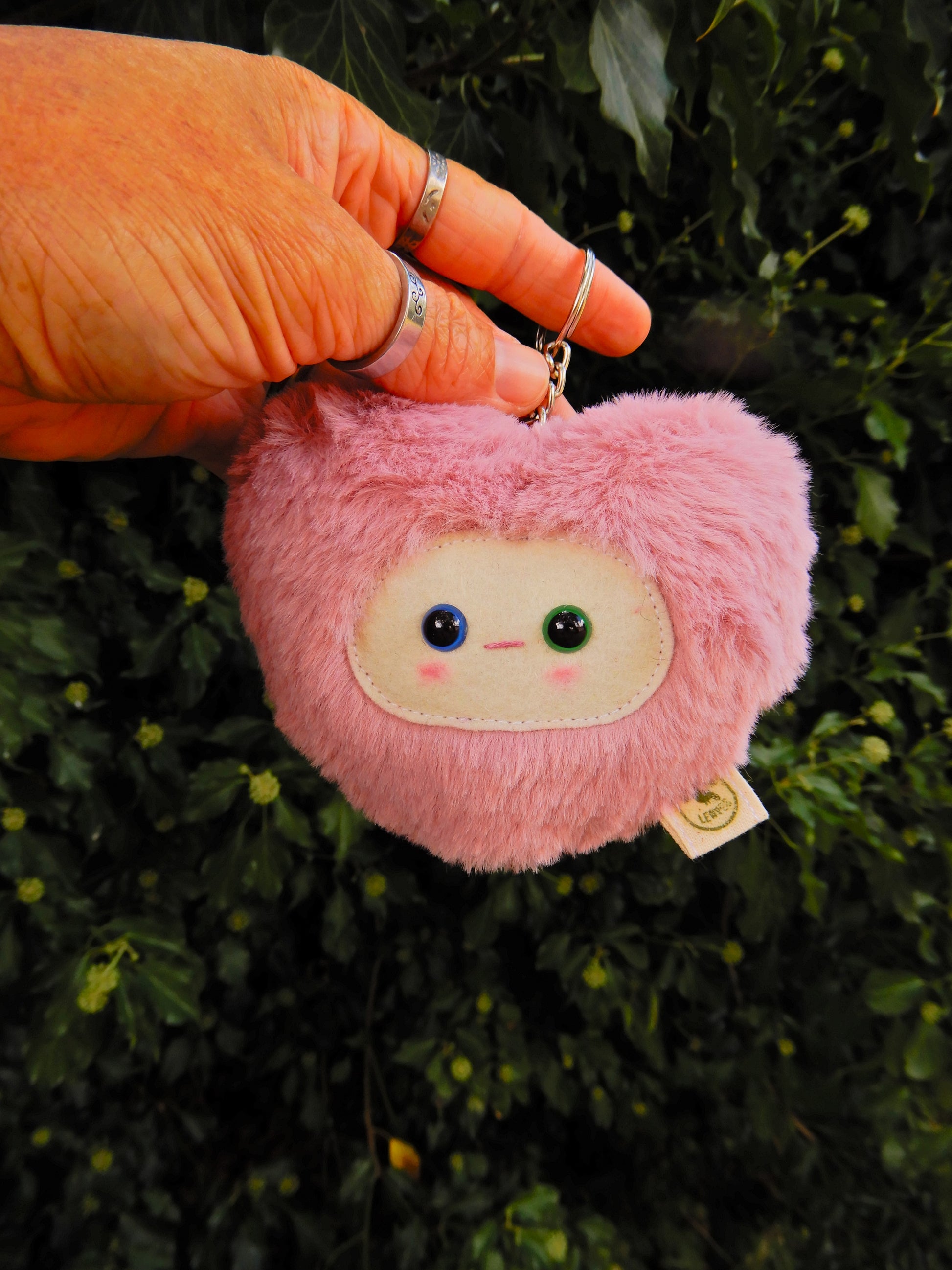 Pink plush key chain/ bag charm with a face design.