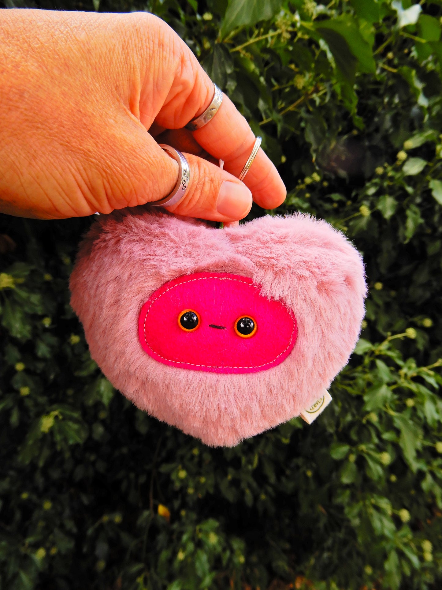 Pink heart shaped plush key chain/ bag charm with a deep pink face.