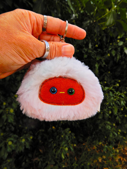 A light rainbow plush keychain/bag charm with a brown face and pink cheeks.
