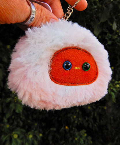 A light rainbow plush keychain/bag charm with a brown face and pink cheeks.