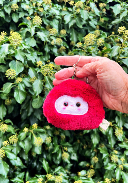 A red fluffy keychain/ bag charm with a white face and shiny eyes. 