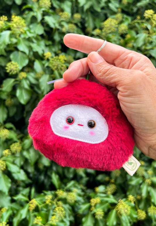 A red fluffy keychain/ bag charm with a white face and shiny eyes. 